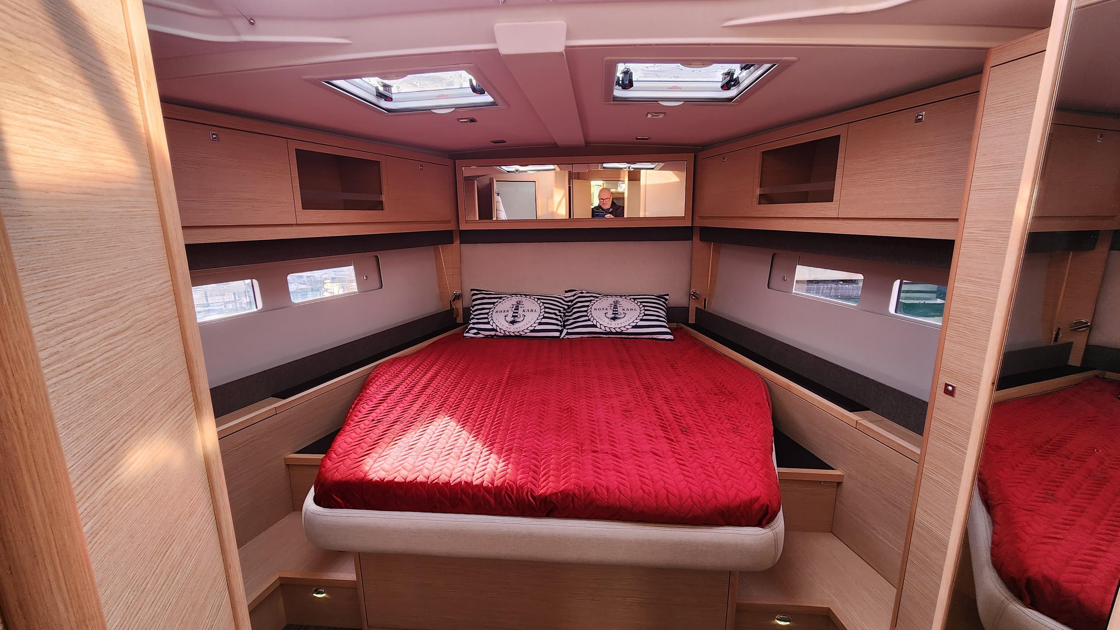 Luxurious cabin interior of 2023 Dufour 530 yacht with red bedding and modern design.