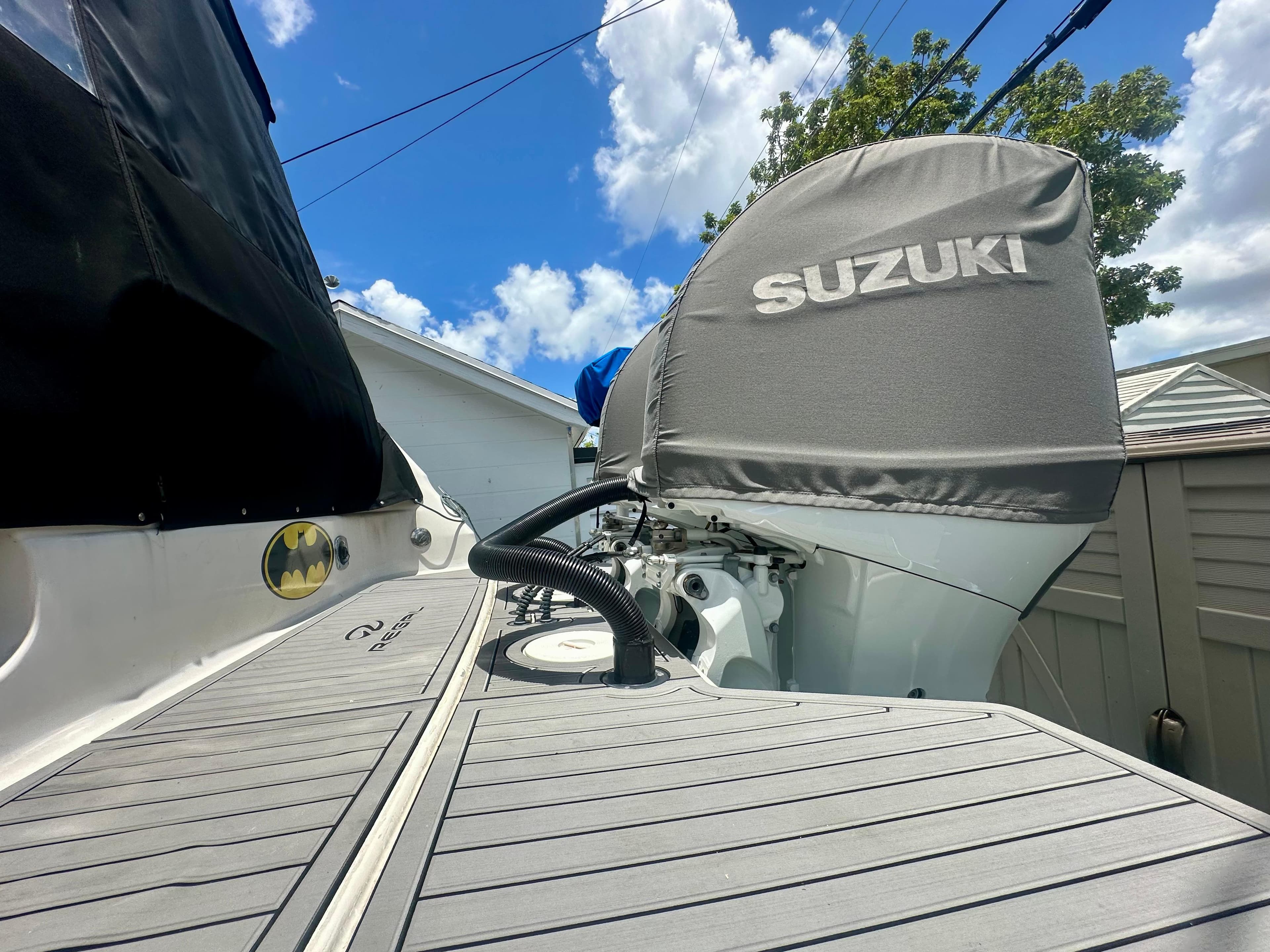 2001 Regal Commodore 2760 boat with Suzuki engine cover, docked under a blue sky.