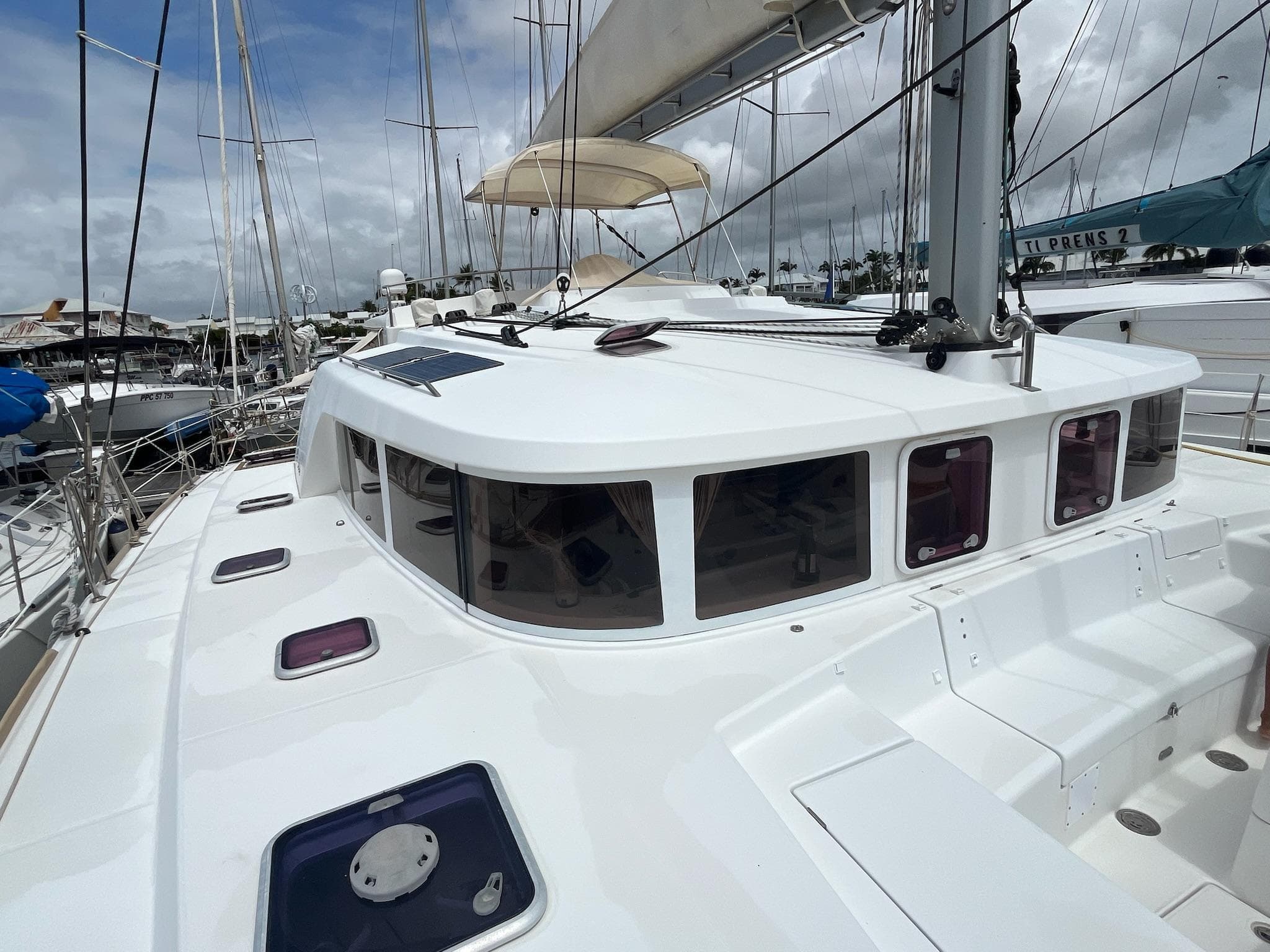 2009 Lagoon 440 catamaran docked at marina, featuring sleek white design and spacious deck.