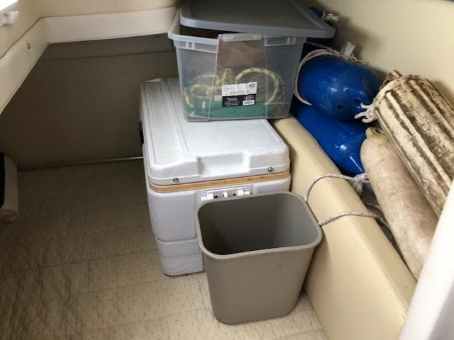 Interior storage area of a 2007 Bayliner 275 boat with cooler, bin, and fenders.