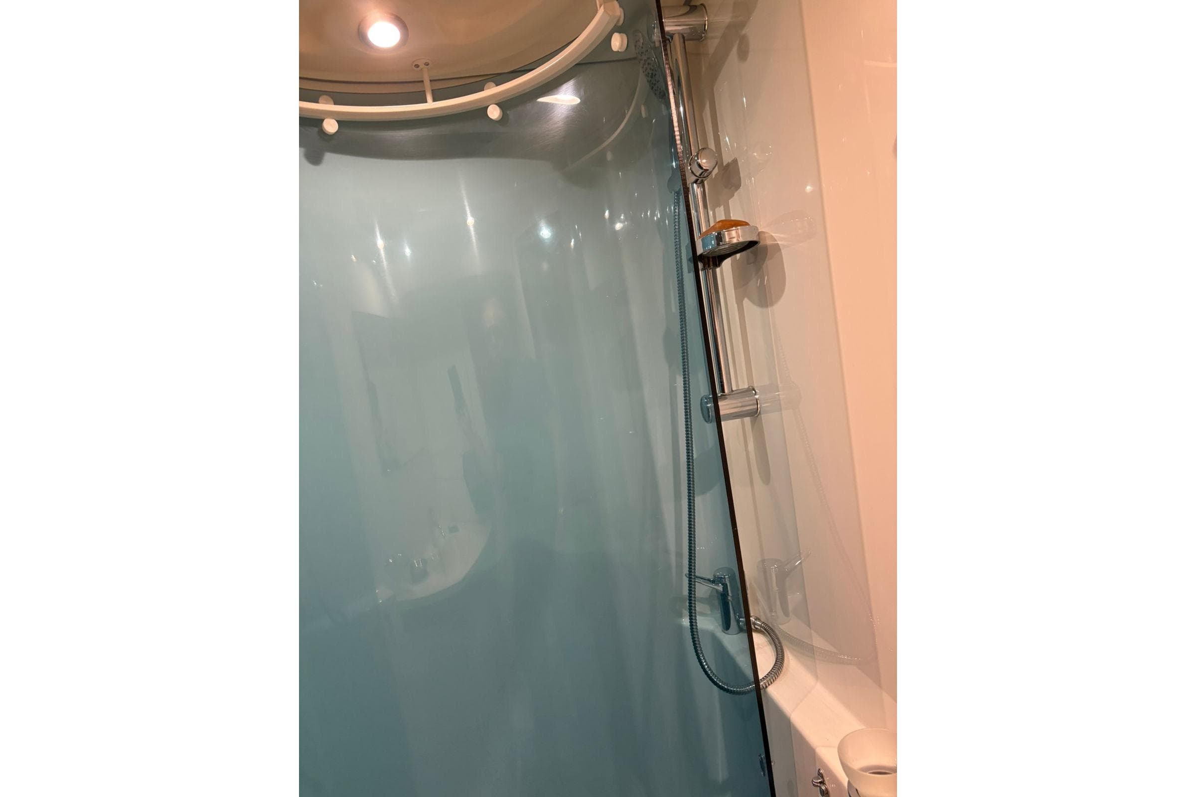 Shower area in 2008 Beneteau 49 yacht with modern fixtures and blue curtain.