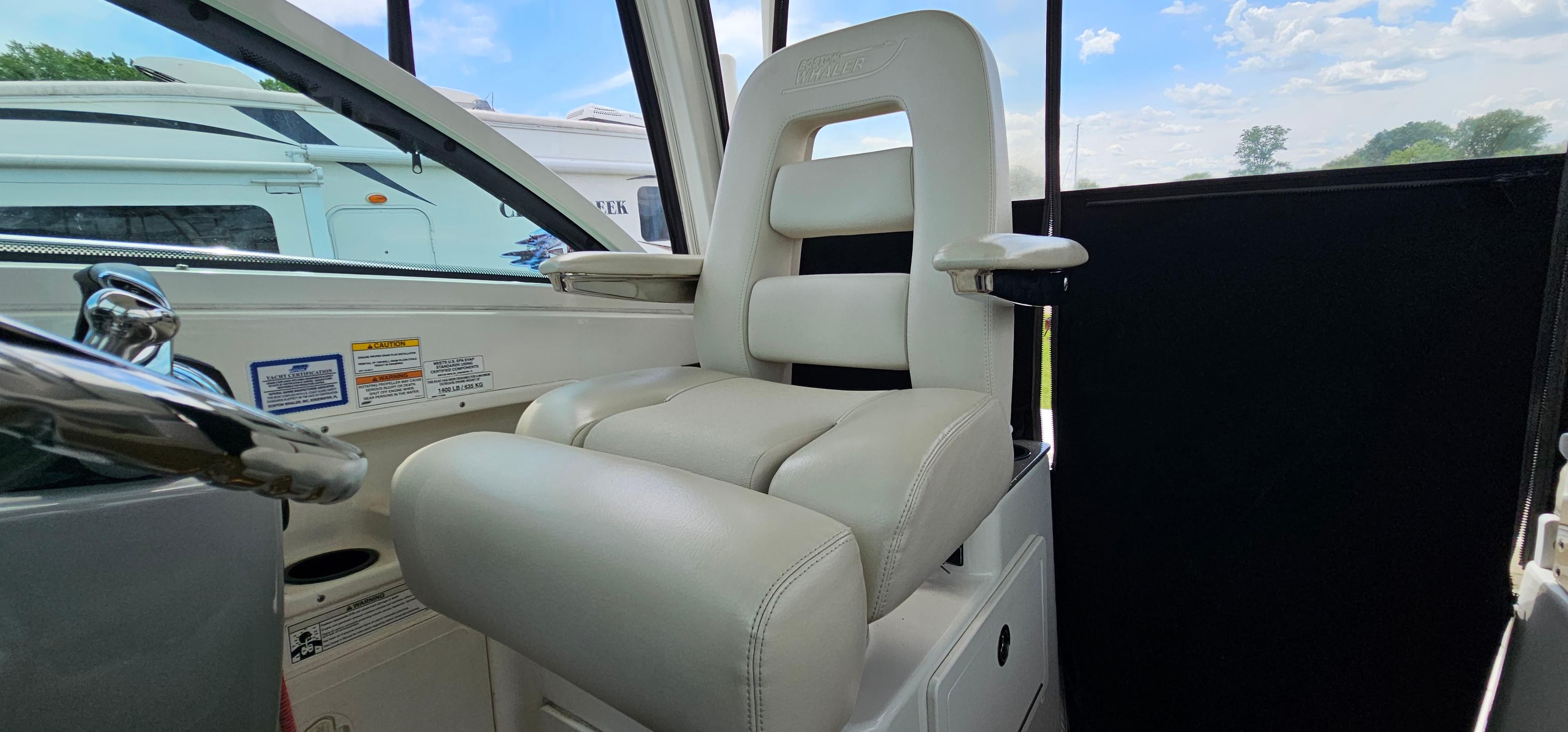 Captain's chair on 2016 Boston Whaler 285 Conquest boat, featuring plush white upholstery.