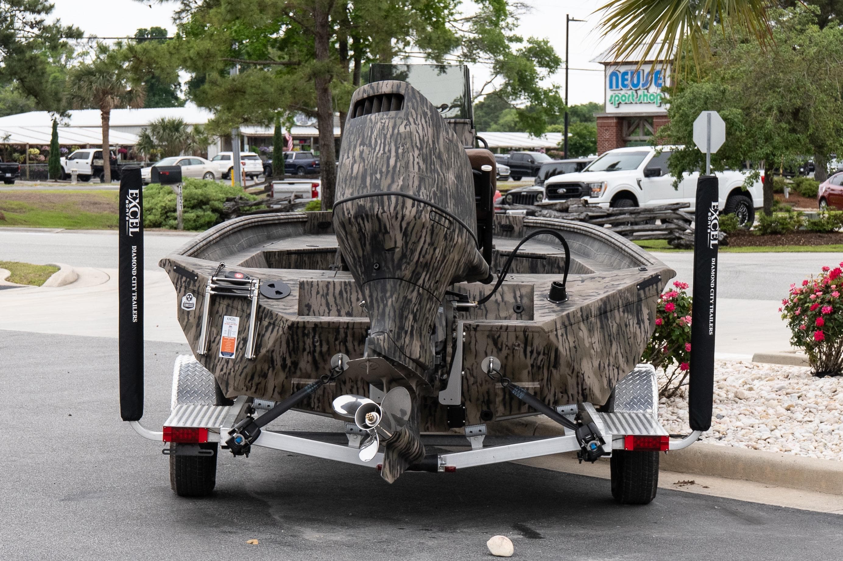 2026 Excel 203 Bay Pro Elite boat on trailer, parked outdoors near a sport shop.