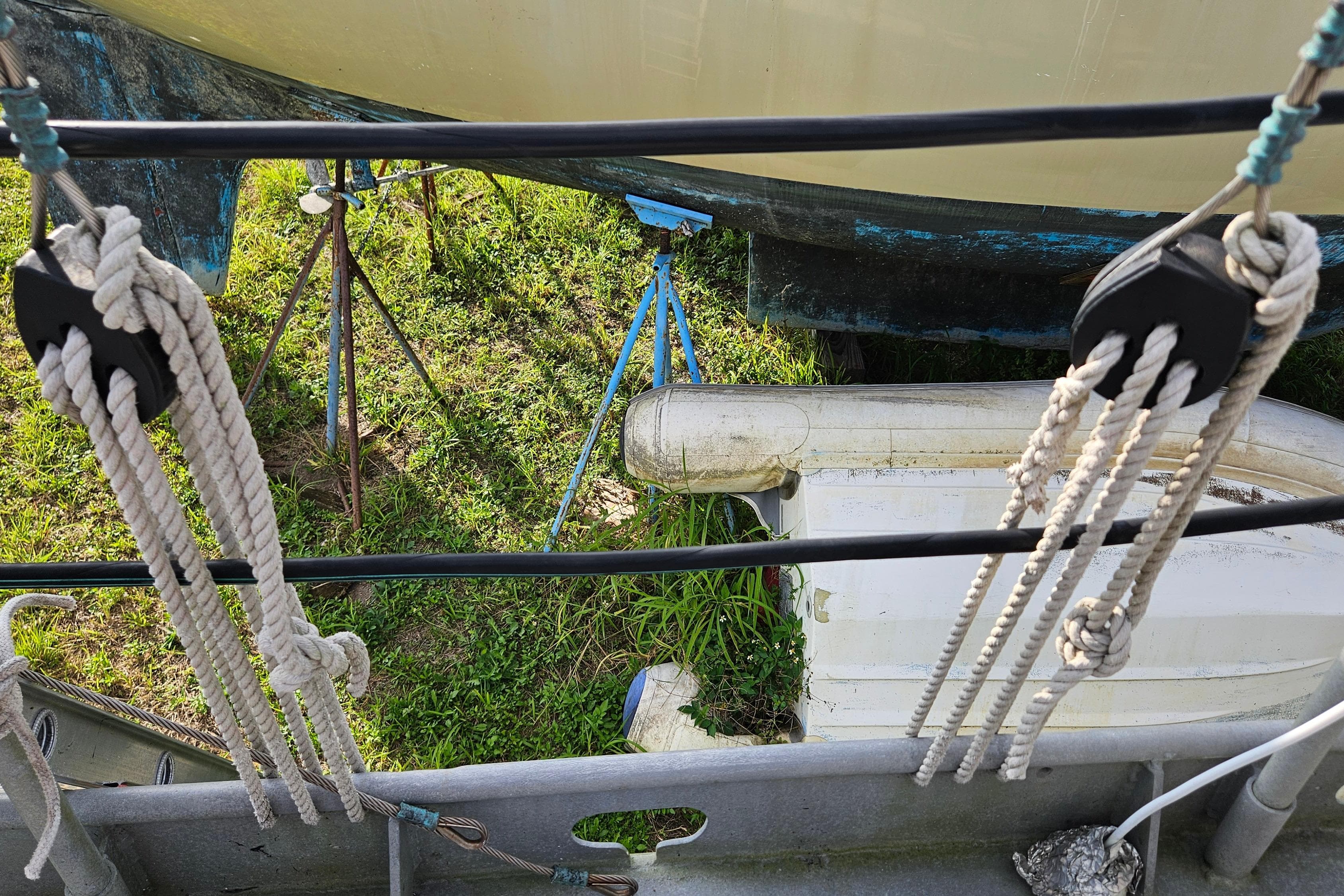 Ropes and pulleys on a 1974 Colvin Gazelle Custom boat, with grass and equipment below.