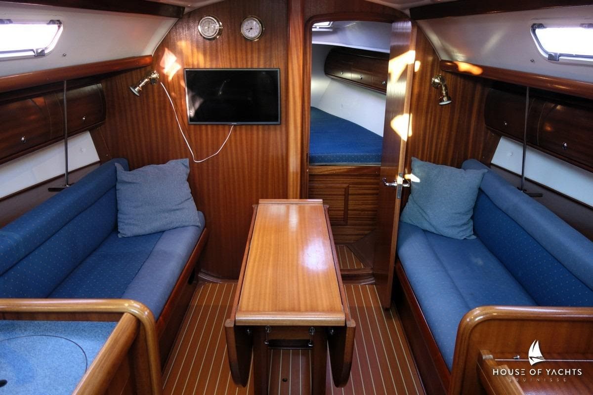Interior of 2003 Bavaria 32 yacht with wooden finish and blue seating.
