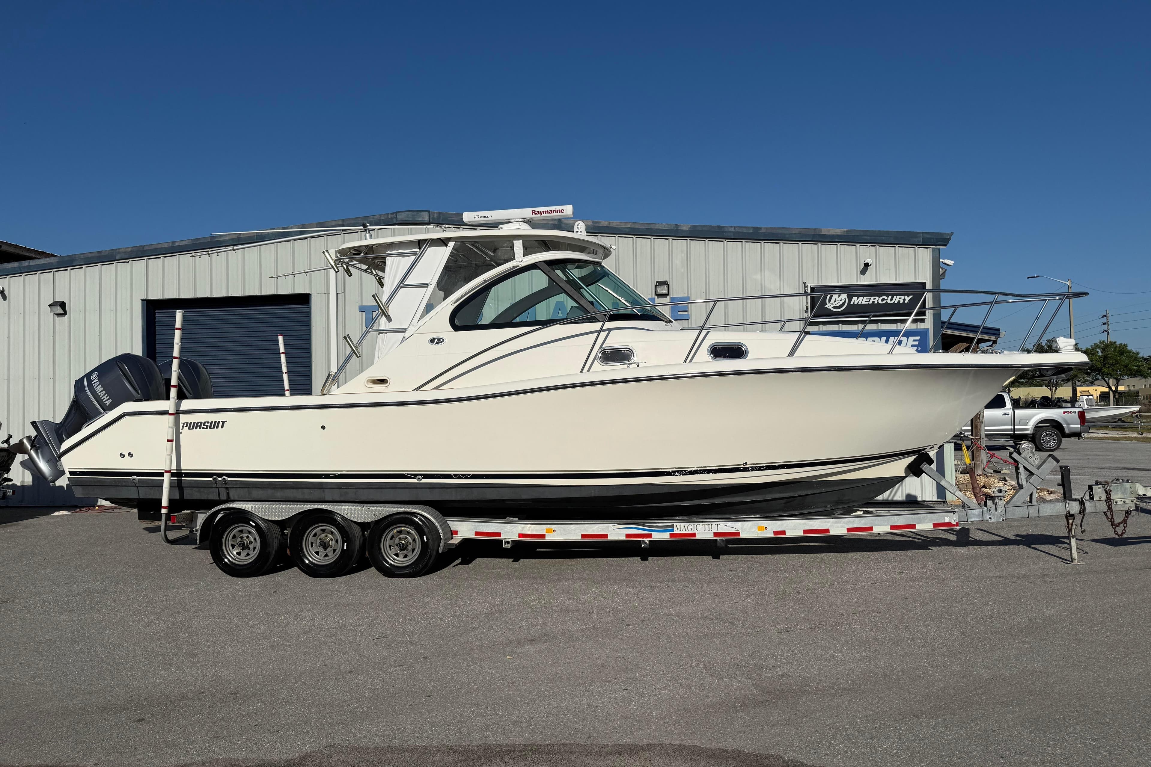 2007 Pursuit OS 335 Offshore boat on trailer, parked outside a metal building.