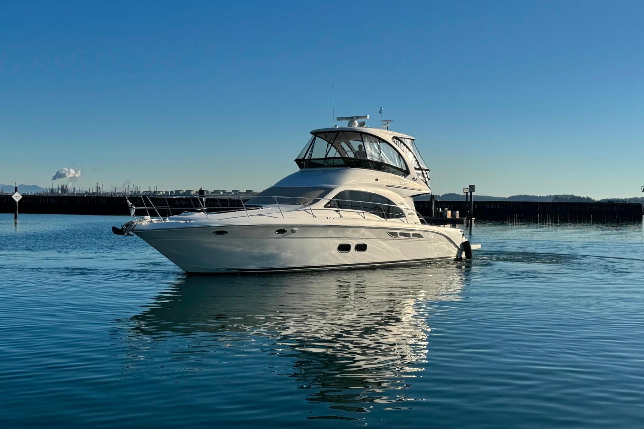 2010 Sea Ray 520 Sedan Bridge yacht cruising on calm waters under clear blue sky.
